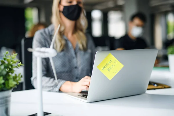 Neznámá mladá žena s obličejovou maskou zpět v práci v úřadu po uzamčení. — Stock fotografie
