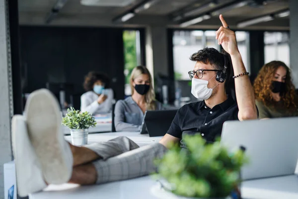 Young people with face masks back at work or school in office after lockdown, having fun. — Stock Photo, Image