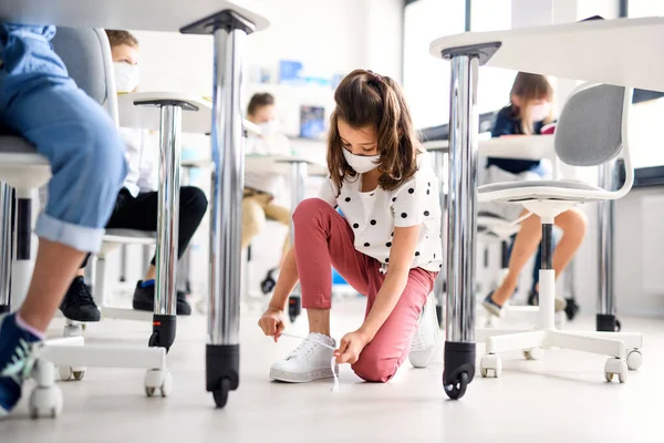 Kind met gezichtsmasker terug op school na covid-19 lockdown, veters strikken. — Stockfoto