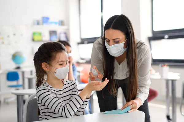 Maestra y niños con mascarilla en la escuela, manos desinfectadas . — Foto de Stock