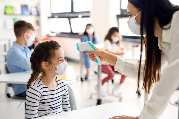 Maestro, niño con mascarilla facial en la escuela después de la cuarentena de covid-19, medición de la temperatura . — Foto de Stock