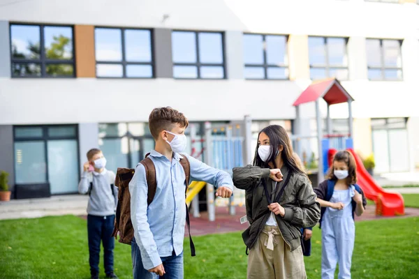 Crianças com máscara facial voltando para a escola após o bloqueio covid-19, saudação . — Fotografia de Stock