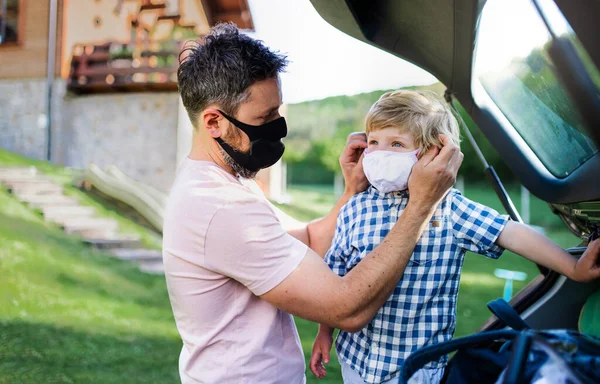 Ojciec z małym synem jedzie na wycieczkę samochodem, w maskach na twarz. — Zdjęcie stockowe