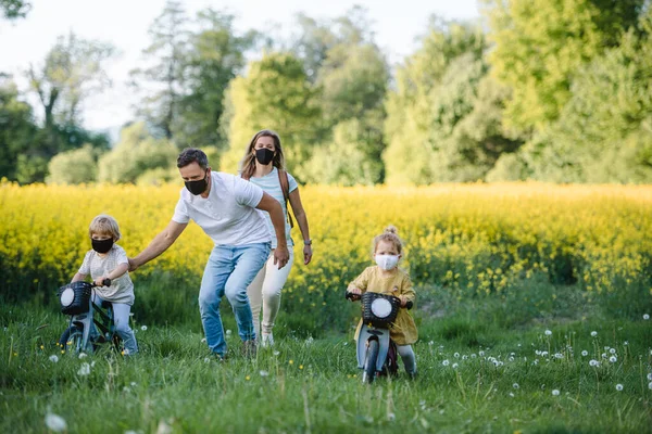 Family with two small children and face masks on cycling trip in countryside. — Stock Photo, Image