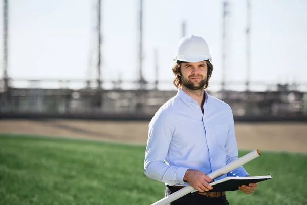 Ingeniero joven con sombrero duro parado al aire libre por la refinería de petróleo . — Foto de Stock