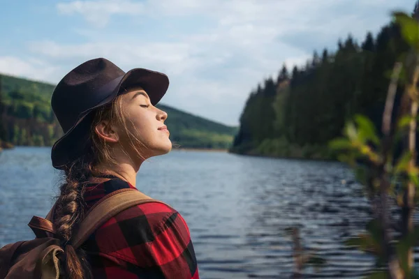 Mujer joven de pie al aire libre junto al lago en un paseo en la naturaleza de verano, relajante . —  Fotos de Stock