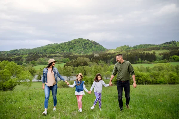 Happy family with two small daughters walking outdoors in spring nature. — Stock Photo, Image