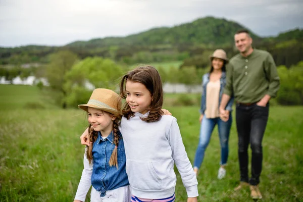 Famille heureuse avec deux petites filles marchant à l'extérieur dans la nature printanière . — Photo