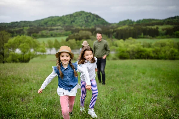 Happy family with two small daughters running outdoors in spring nature. — Stock Photo, Image