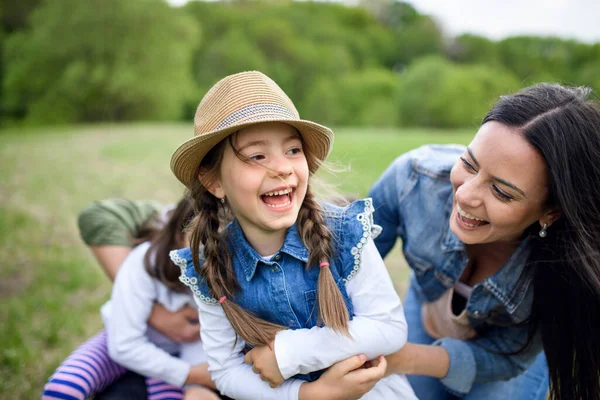 Szczęśliwa rodzina z dwiema małymi córkami bawiącymi się na świeżym powietrzu w wiosennej przyrodzie. — Zdjęcie stockowe