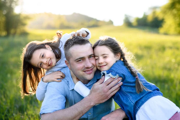 Père avec deux petites filles s'amusant à l'extérieur dans la nature printanière, étreignant . — Photo