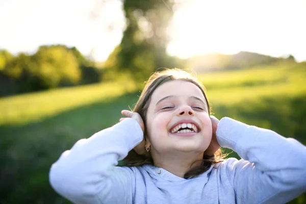 Portrait de petite fille debout à l'extérieur dans la nature printanière, s'amuser . — Photo