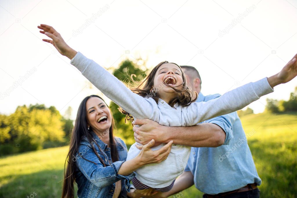 Happy family with small daughter having fun outdoors in spring nature.