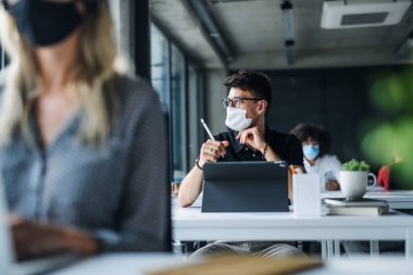 Yüzü maskeli gençler iş yerinde ya da okul kapandıktan sonra ofiste..