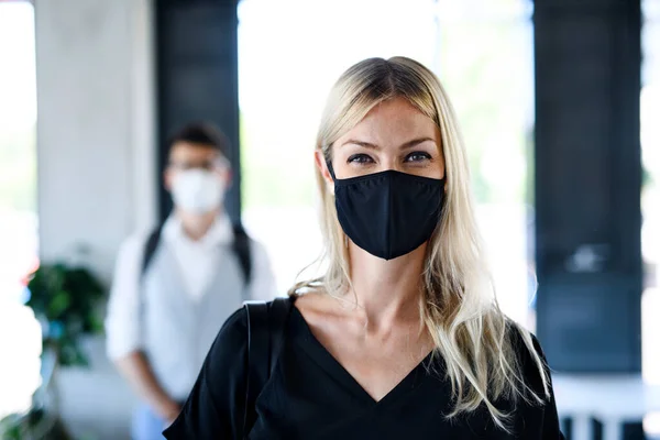 Young woman with face mask back at work in office after lockdown, looking at camera. — Stock Photo, Image