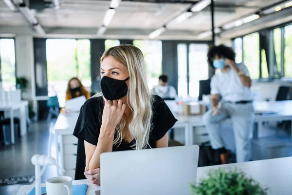 Jovem com máscara facial de volta ao trabalho no escritório após o bloqueio. — Fotografia de Stock