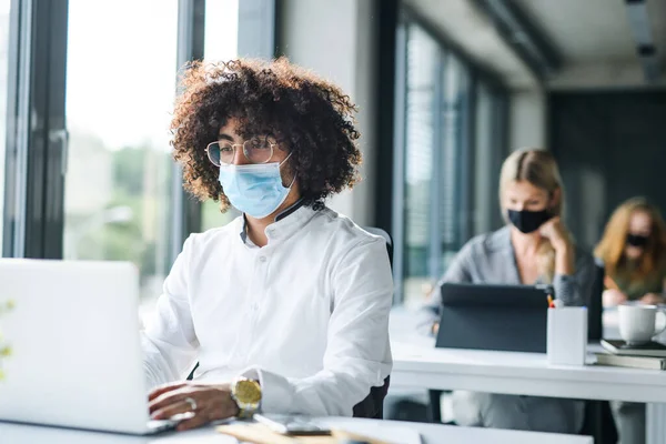 Porträtt av ung man med ansiktsmask tillbaka på jobbet efter nedlåsning. — Stockfoto