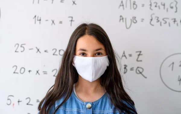 Menina com máscara facial de volta à escola após quarentena e bloqueio covid-19. — Fotografia de Stock