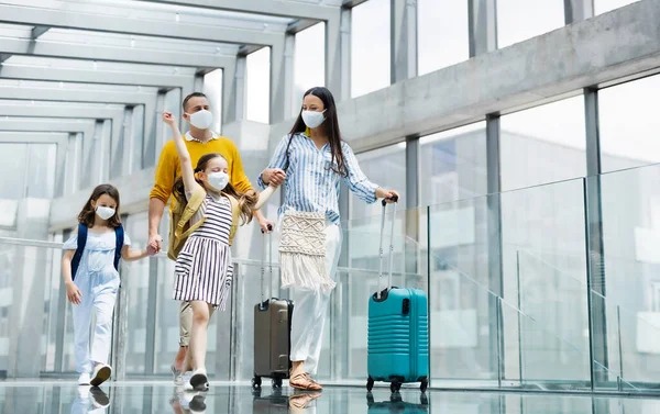 Familia con dos hijos de vacaciones, con mascarillas en el aeropuerto . — Foto de Stock