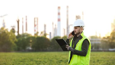 Akıllı telefonu olan genç bir mühendis petrol rafinerisinin önünde bekliyor. Boşluğu kopyala.