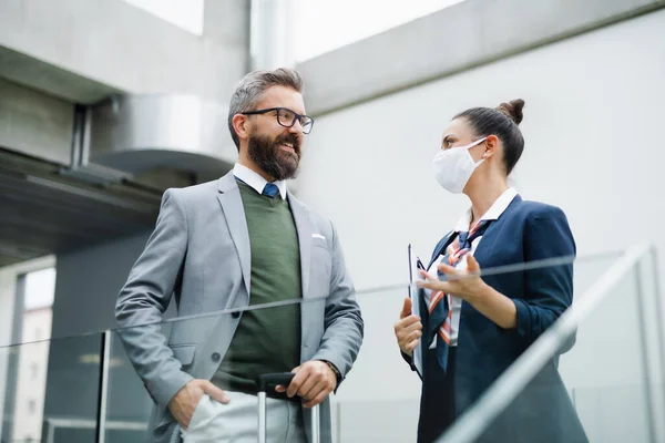 Flight attendant talking to businessman on airport, wearing face masks. — Stock Photo, Image