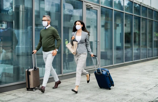 Empresarios con equipaje en viaje de negocios, con mascarillas en el aeropuerto . — Foto de Stock