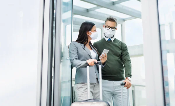 Бизнесмены с багажом отправляются в командировку, носят маски в аэропорту . — стоковое фото