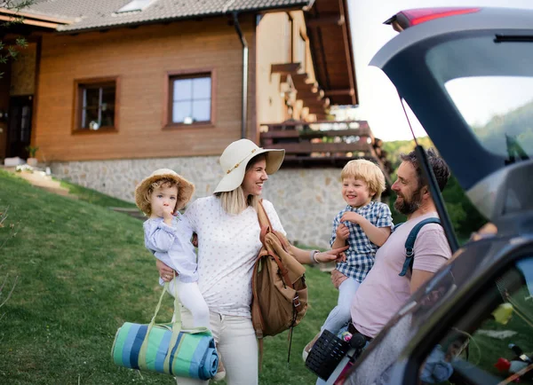 Rodina se dvěma malými dětmi nakládá auto na výlet do přírody. — Stock fotografie