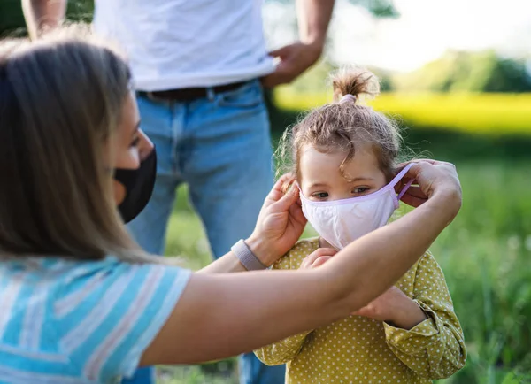 Family with small daughter on trip in nature, wearing face masks. — Stock Photo, Image