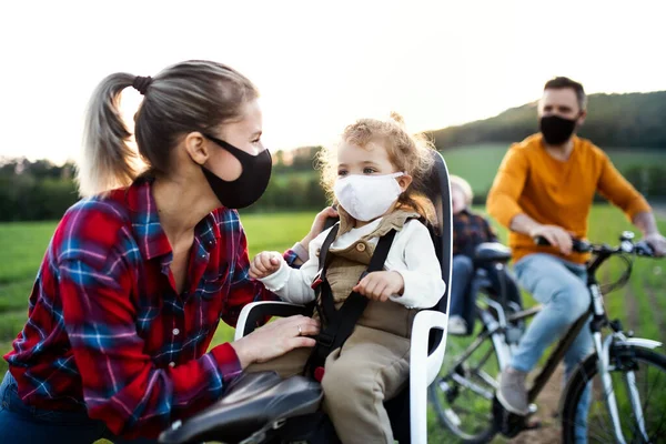 Gezin met twee kleine kinderen op fietstocht, met gezichtsmaskers op. — Stockfoto