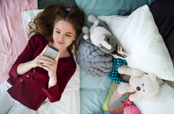 幸せな若い女の子の笑顔のトップビューとベッドの上で自撮り,オンラインデートのコンセプト. — ストック写真