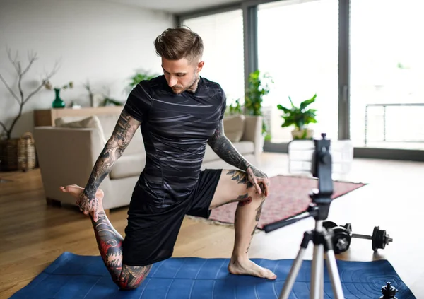 Man trainer doing online workout exercise indoors at home, using camera. — Stock Photo, Image