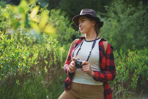 Mujer joven con cámara en un paseo por el bosque en la naturaleza de verano, de pie . —  Fotos de Stock