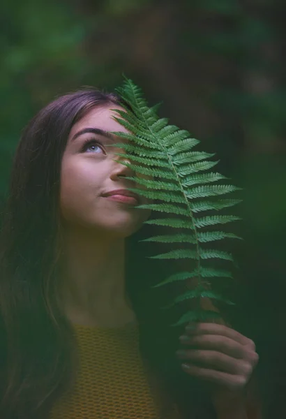 Genç bir kadının yakın plan portresi. Doğada bir ormanda, elinde eğreltiotu tutarken.. — Stok fotoğraf