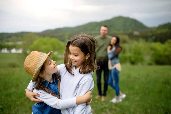 Familia feliz con dos hijas pequeñas caminando al aire libre en la naturaleza de primavera . — Foto de Stock