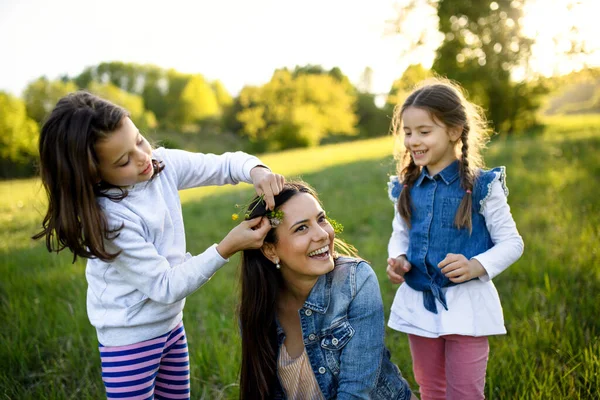 Mor med två små döttrar som har roligt utomhus i vårnaturen. — Stockfoto