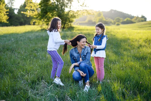 Madre con due piccole figlie che si divertono all'aperto nella natura primaverile . — Foto Stock