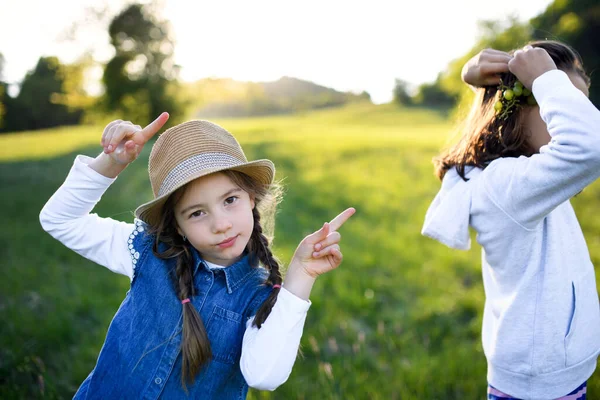 Portrét dvou malých dívek stojících venku v jarní přírodě, bavících se. — Stock fotografie