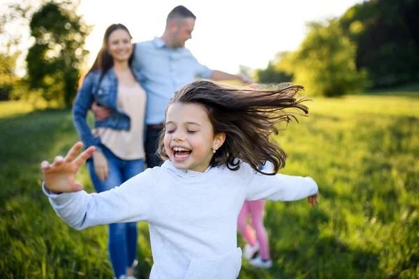 Familia feliz con dos hijas pequeñas divirtiéndose al aire libre en la naturaleza de primavera . — Foto de Stock
