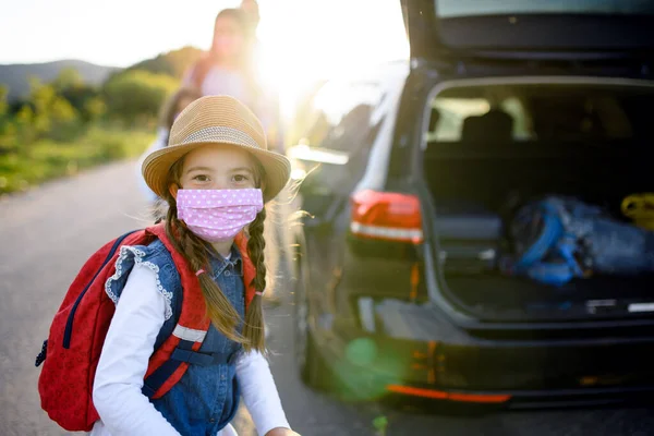 Malá dívka s rodinou na výletě venku v přírodě, s obličejovými maskami. — Stock fotografie