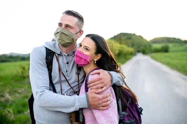 Casal feliz em viagem ao ar livre na natureza, usando máscaras faciais . — Fotografia de Stock