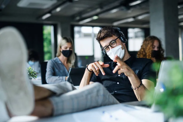 Jongeman met gezichtsmasker weer aan het werk of school in het kantoor na afsluiting, plezier hebben. — Stockfoto