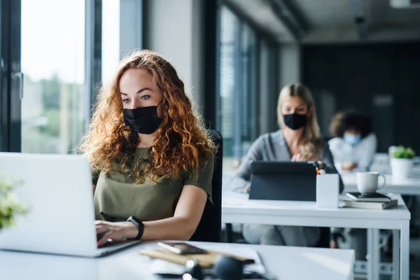 Mladí lidé s obličejovými maskami zpět v práci nebo ve škole v úřadu po uzavření. — Stock fotografie