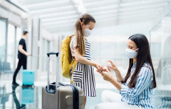 Madre e hija con mascarilla en vacaciones, manos desinfectadas en el aeropuerto . — Foto de Stock