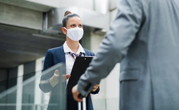 Flight attendant talking to unrecognizable businessman on airport, wearing face masks. — Stock Photo, Image