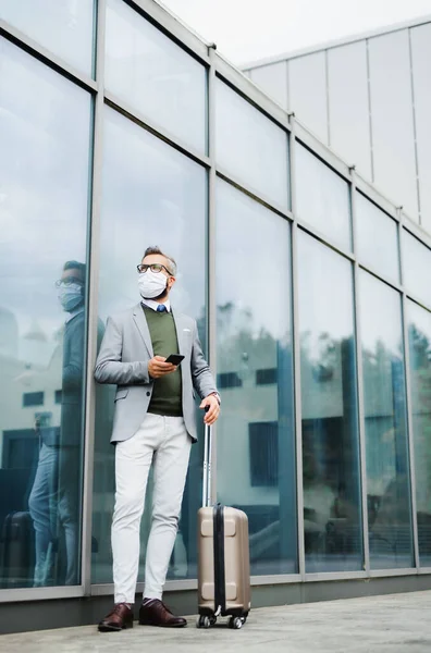 Empresario con equipaje en viaje de negocios, con mascarilla en el aeropuerto . — Foto de Stock