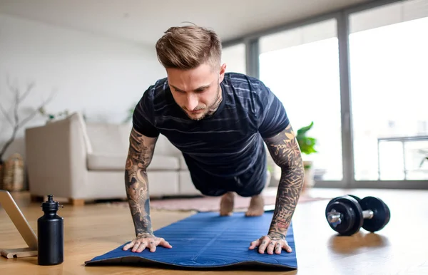 Vue de face portrait de l'homme avec tablette faire de l'exercice à l'intérieur à la maison. — Photo