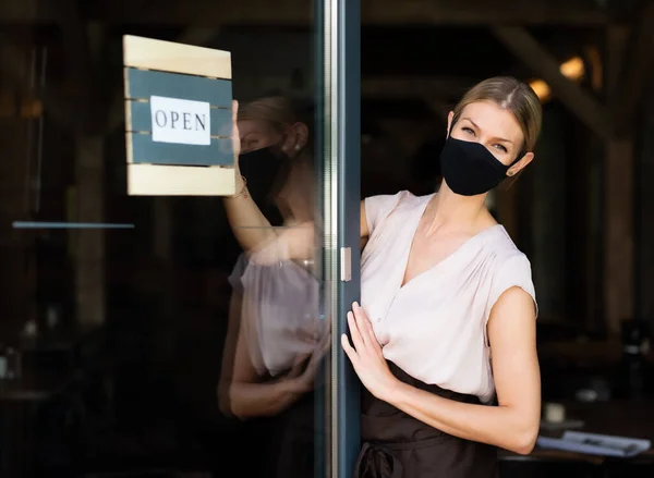 Portrait of waitress with face mask standing at the door in restaurant. — Stock Photo, Image