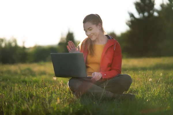 Gelukkige jonge vrouw met behulp van laptop buiten in de zomer natuur, video call concept. — Stockfoto