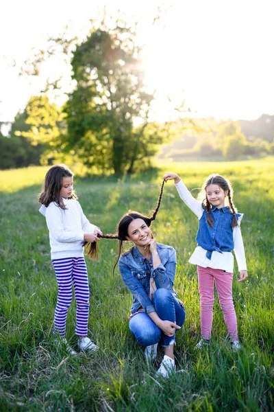 Mãe com duas filhas pequenas se divertindo ao ar livre na natureza primavera . — Fotografia de Stock